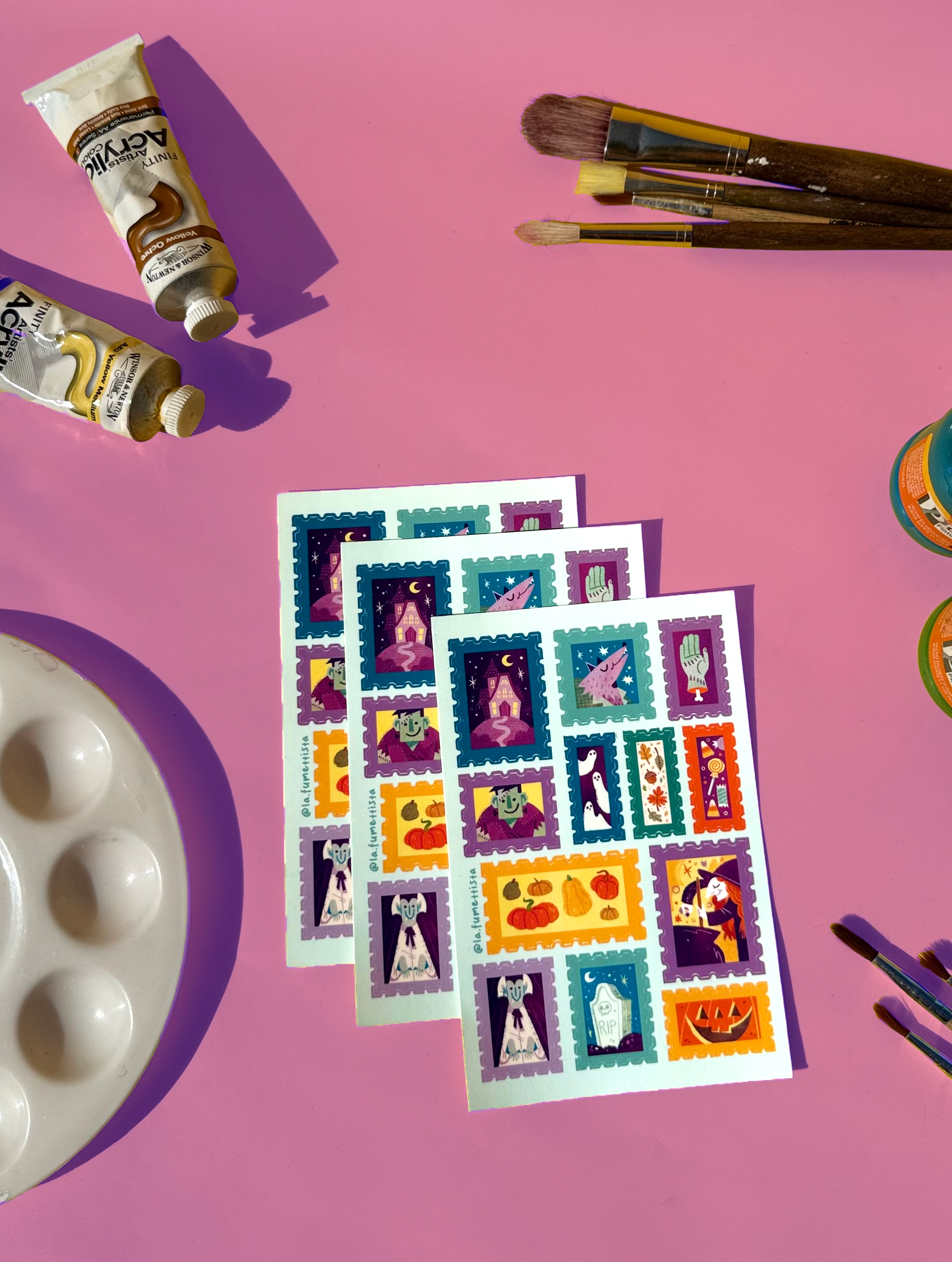 Colorful stamp designs on a pink background with art supplies.